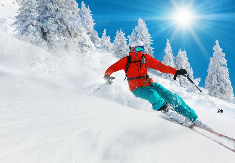 Person skiing down a mountain on a sunny day.