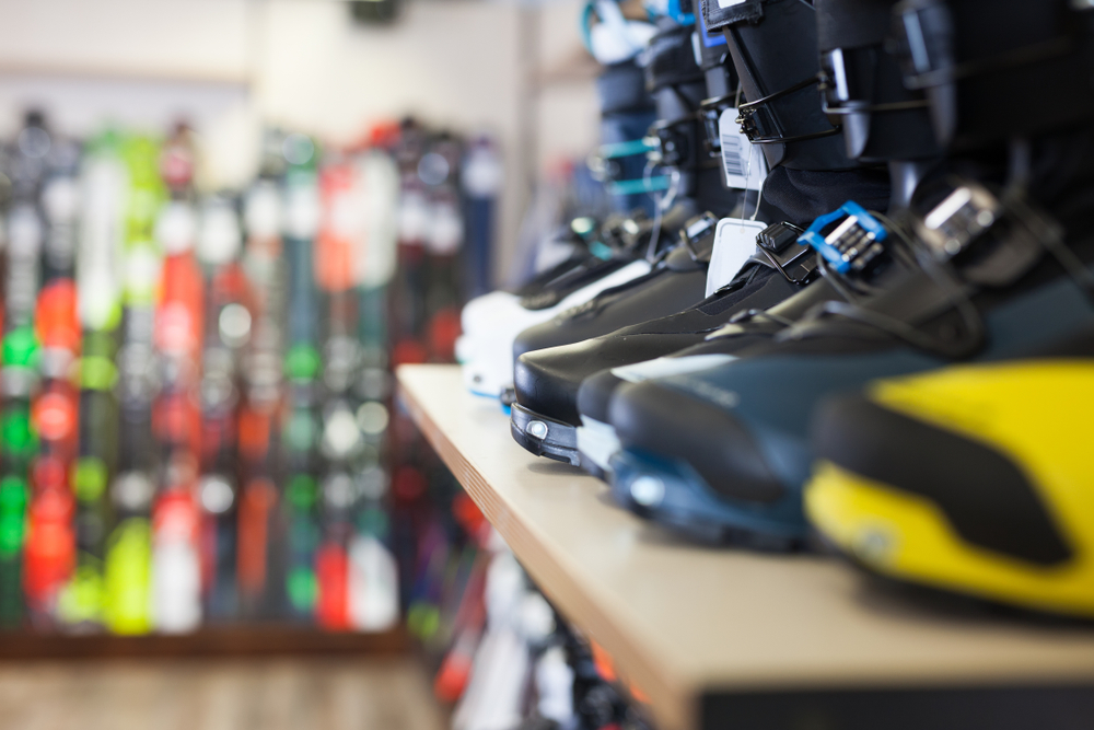 Boots sitting on a shelf with a blurred background of other products in the ski retail store.